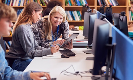 An image of two women talking together in a library area by computers