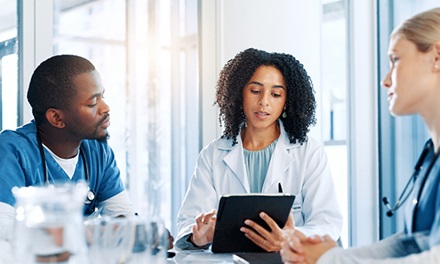 A medical group of people talking in discussion with an iPad
