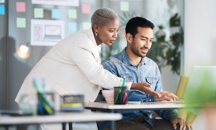 A woman and man collaborating next to a computer screen